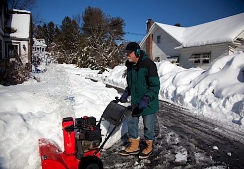Middle-aged man pushing snowblower