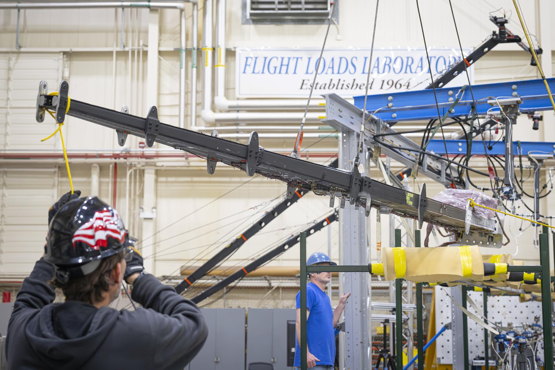 Lab technicians Jeff Howell, left and Chris Mount install the 15-foot Structural Wing Experiment Evaluating Truss-bracing model in the Flight Loads Lab at NASA’s Armstrong Flight Research Center in Edwards, California, Wednesday, February 11, 2026. The model is part of NASA’s research to develop technologies for future ultra-efficient aircraft.NASA/Christopher LC Clark